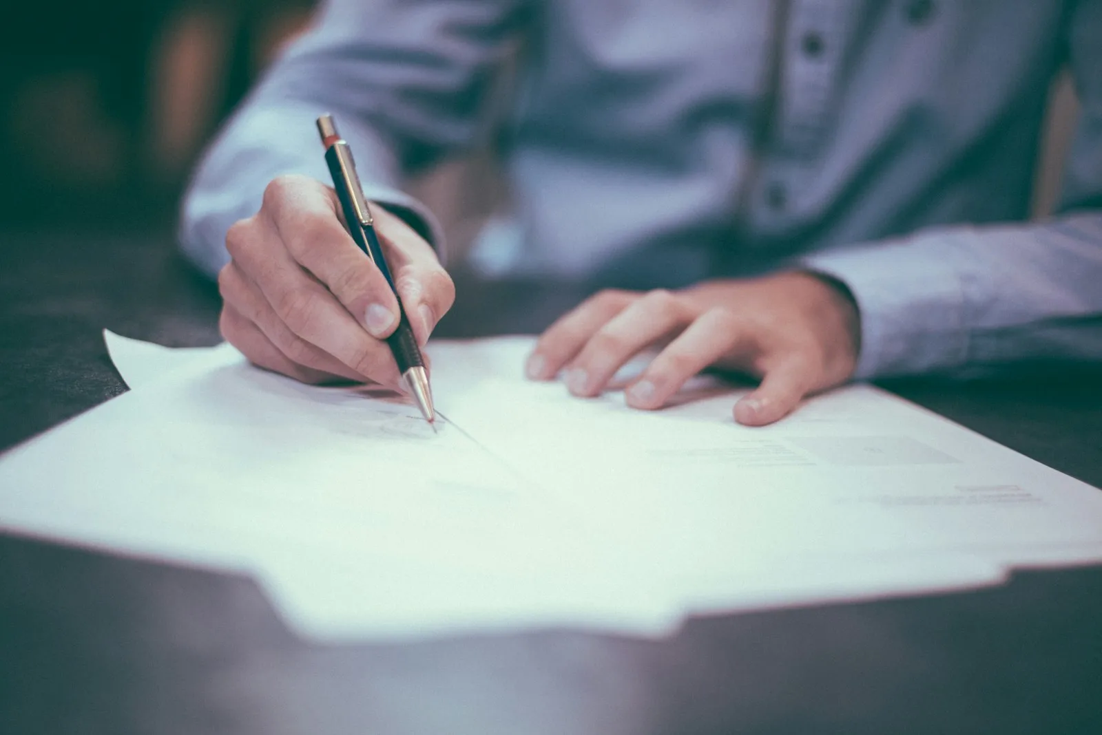 Manos firmando documentos en un despacho profesional